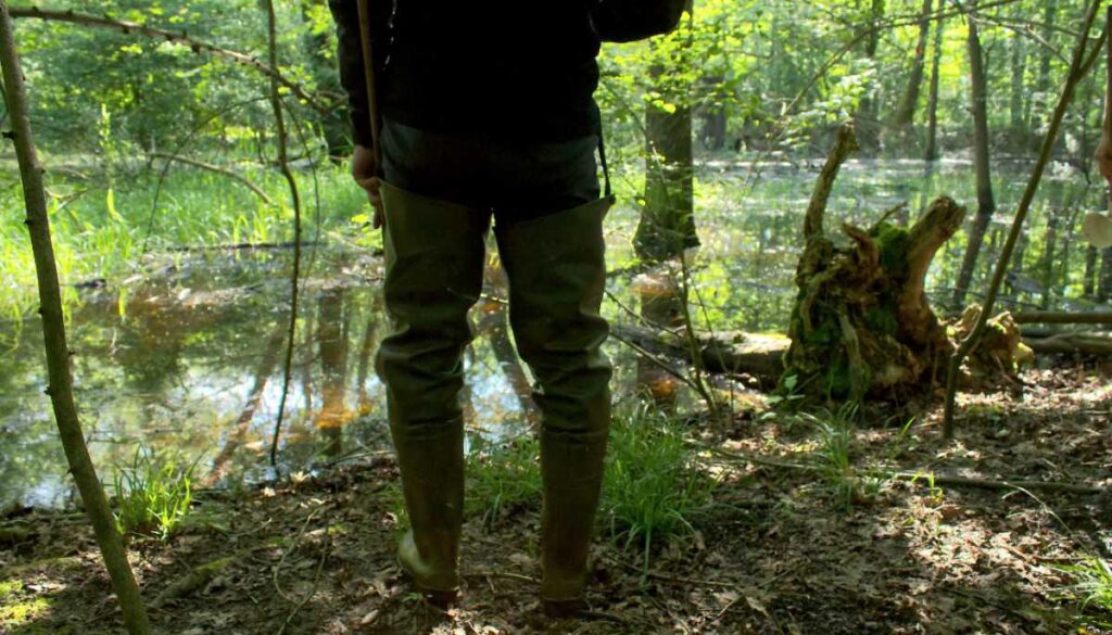 Ein KABS-Mitarbeiter steht in Gummistiefeln vor einer überschwemmten Senke.