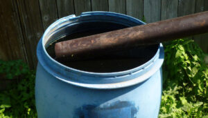 Eine gefüllte Regentonne mit einem Zulaufrohr.