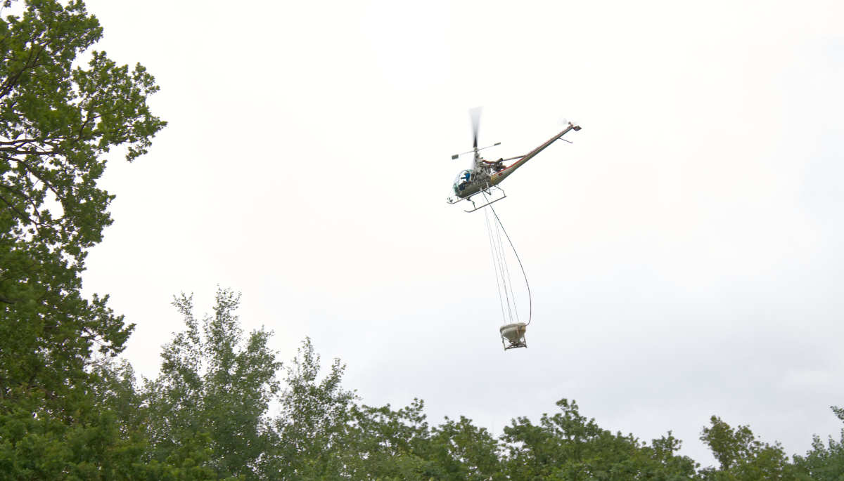 Hiller-Maschine fliegt mit Applikationskübel.