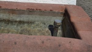 Ruhiges, stehendes Wasser in einem Brunnen.